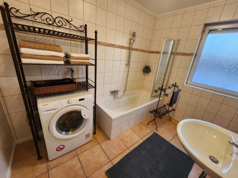 Badezimmer mit Badewanne und Waschmaschine